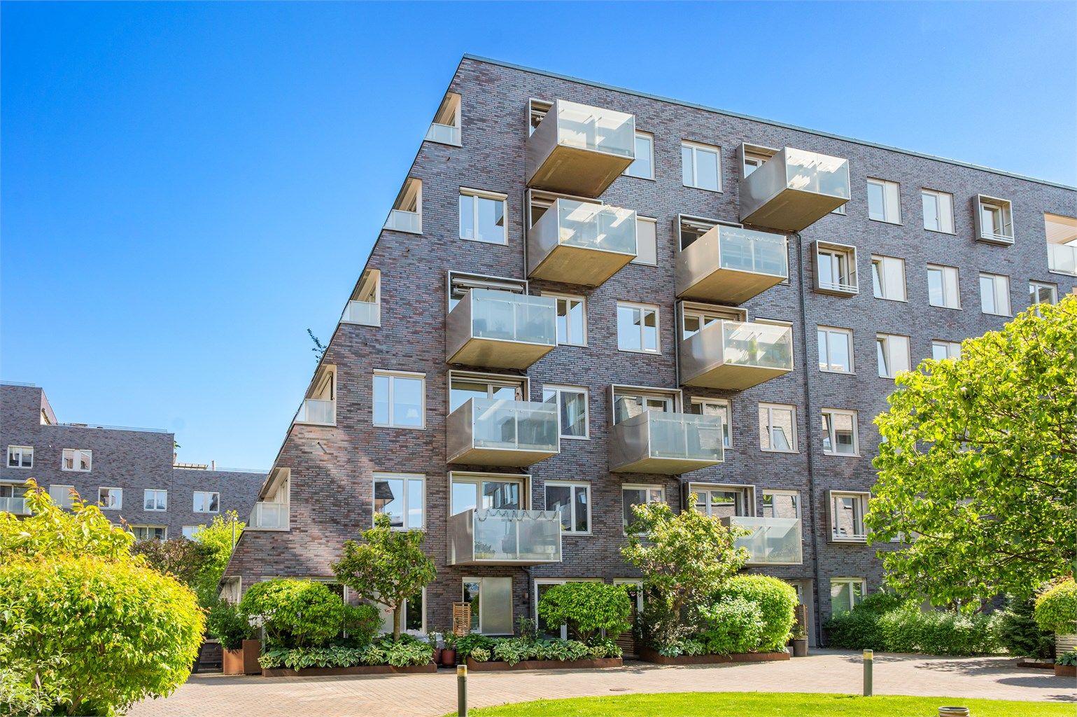 Fasade, leiligheten til venstre. Unik rekkehusfølelse ved direkte adgang til plen og sittegrupper i atriumet. Legg merke til at leiligheten oppleves usjenert. 