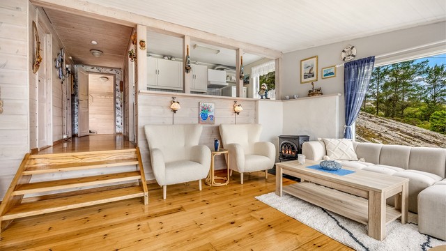 Åpen løsning mellom stue og kjøkken, med nivåforskjell som skaper et naturlig skille.