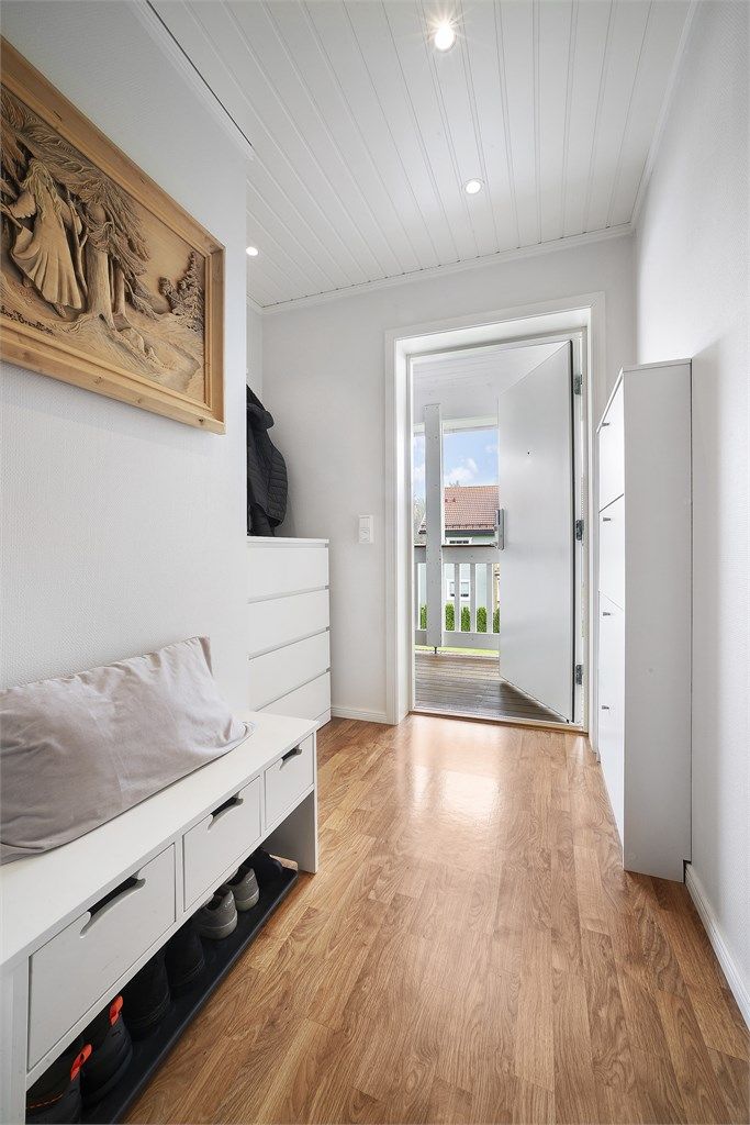 Man kommer inn i en lys og romslig entré med plass til skoskap, kommode og sittebenk