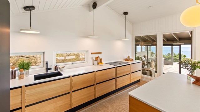 Innredningen er utført i massiv eik med lekre detaljer som fingertappede og solide heltre skuffer. Benkeplaten er i Silestone. Kjøkkenet ble montert i 2021.