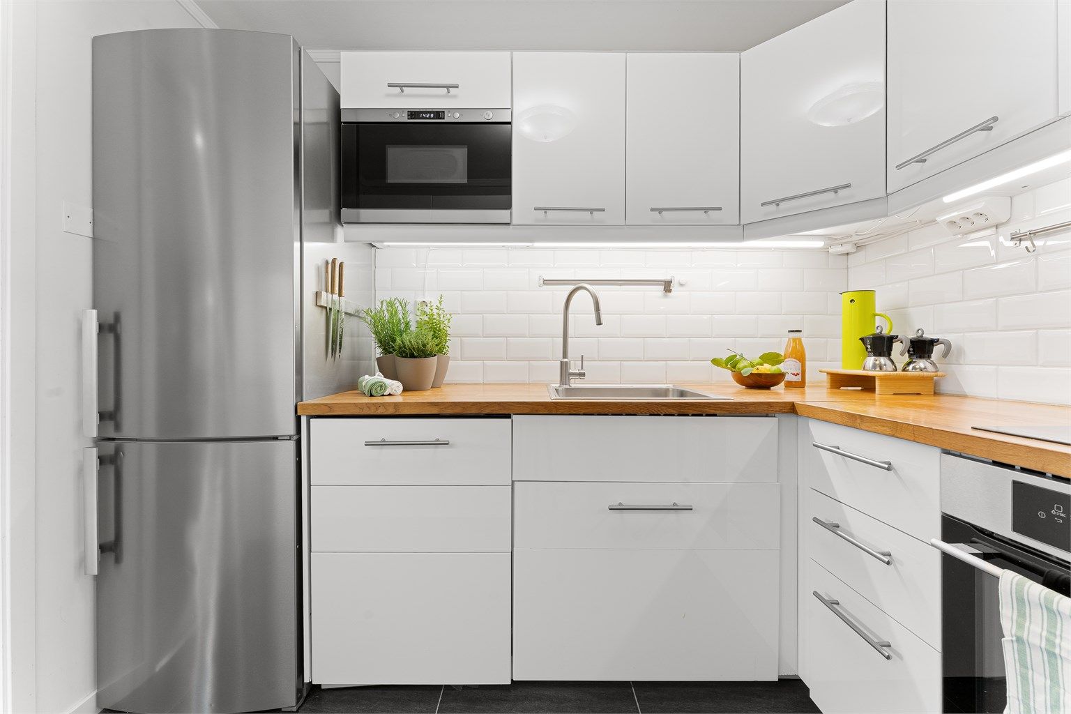 Kjøkkenet har flislagt gulv og delikate fliser mellom benkeplate og overskap.