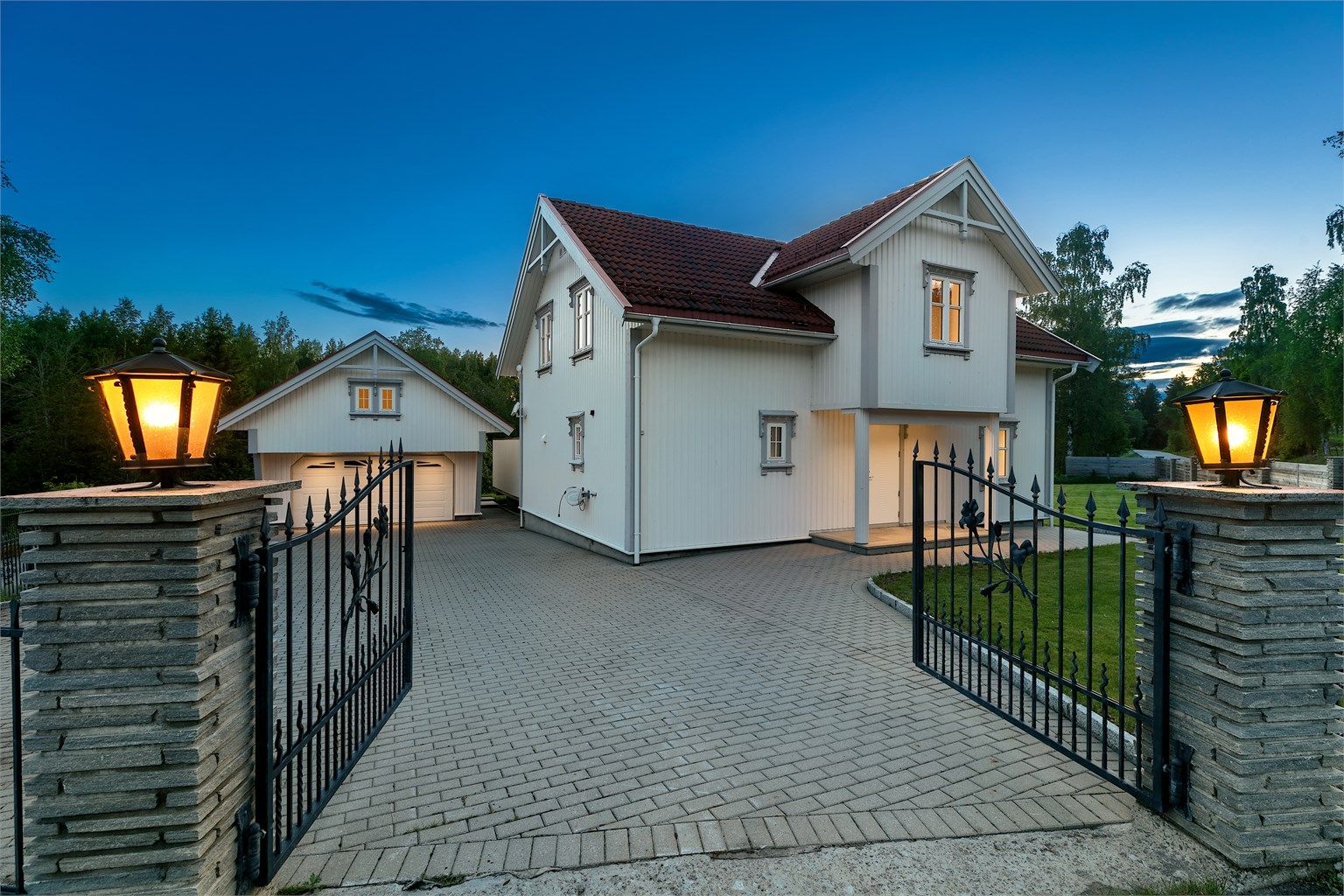 En flott smijernsport tar deg inn på en romslig, steinbelagt gårdsplass.