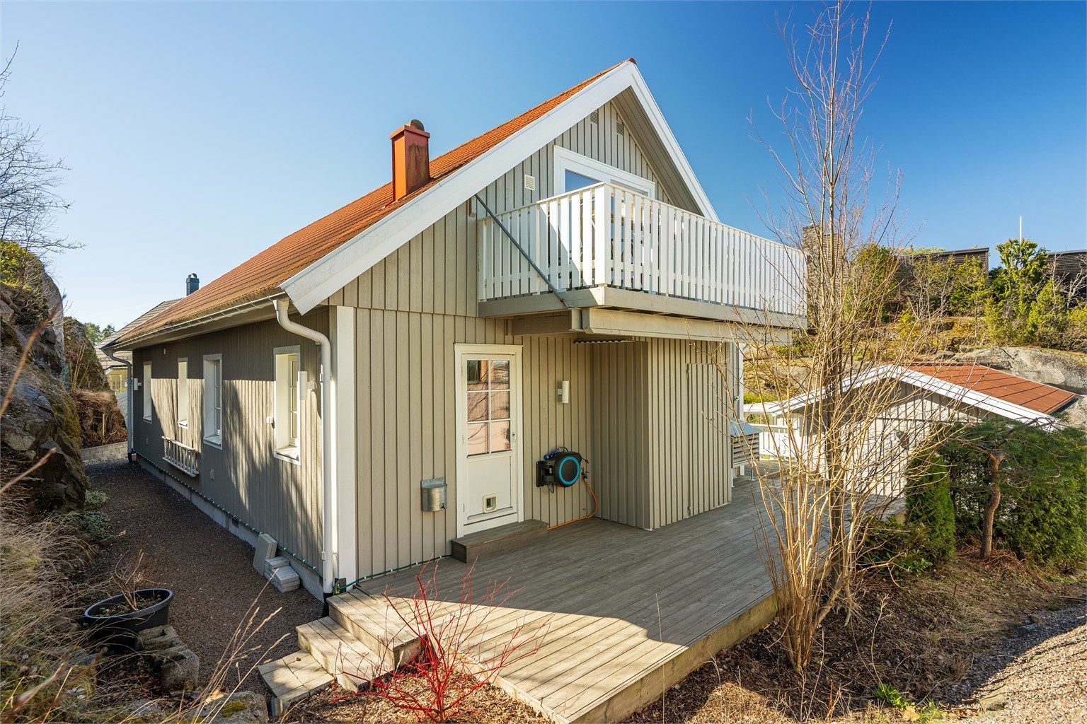 Baksiden av huset med markterrasse og balkongen i loftsetasjen.