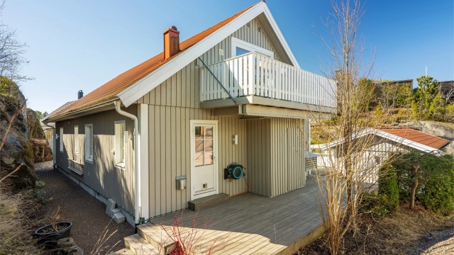 Baksiden av huset med markterrasse og balkongen i loftsetasjen.