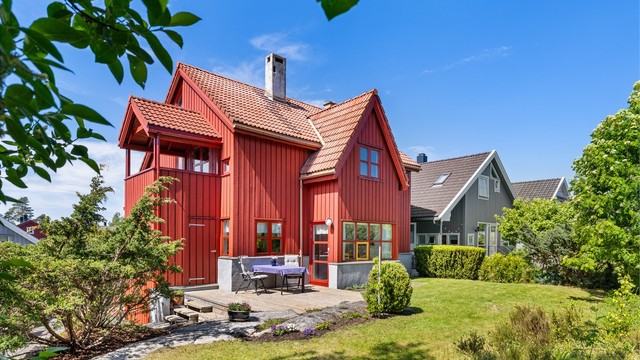 Fasaden er kledd med stående trekledning, og taket har takstein.