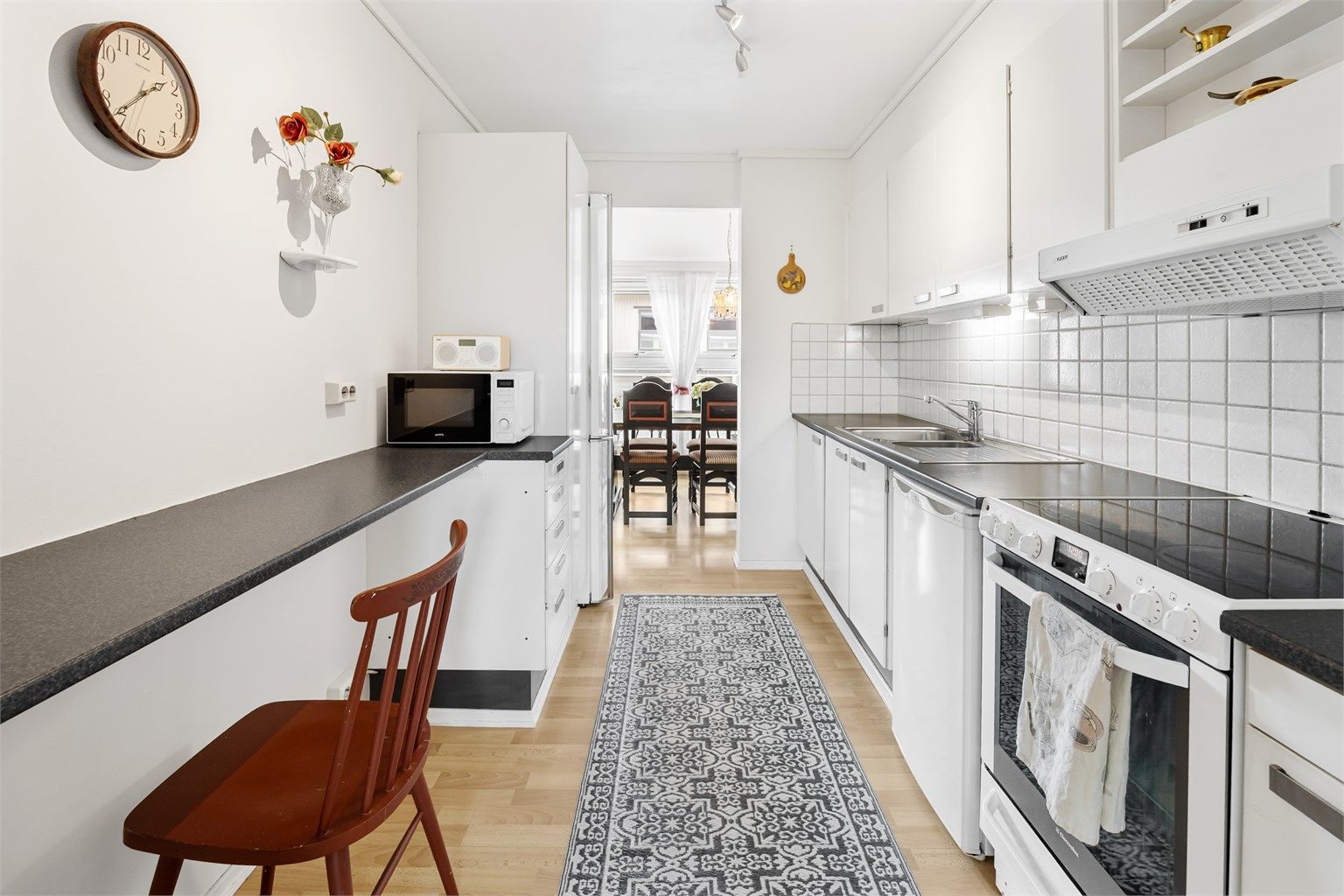 Kjøkkeninnredning med glatte fronter, laminatbenkeplate og fliser over benken.