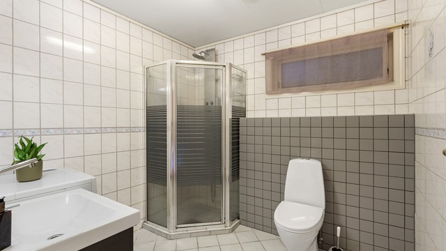 Baderom i underetasjen med flislagte overflater, gulvvarme og dusjhjørne. Rommet er ikke omsøkt/godkjent bruksendret.