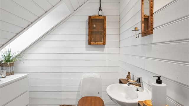 Toalettrom innredet med toalett og vegghengt servant, fungerer som et praktisk tillegg til etasjen