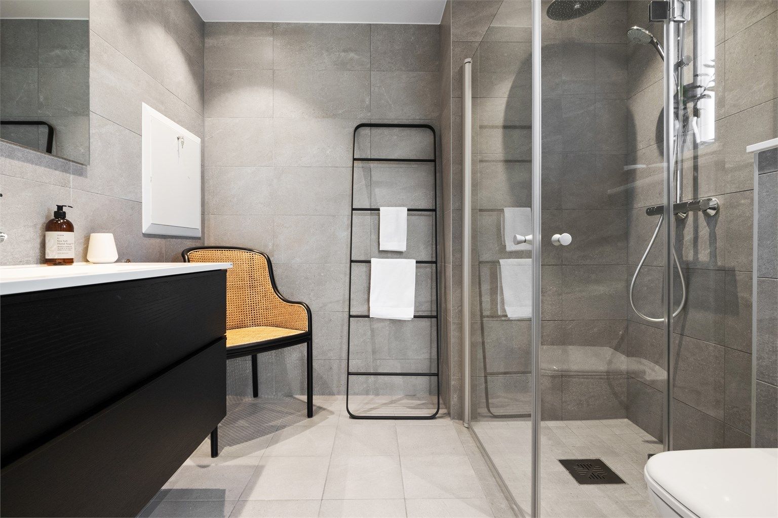 Baderomsinnredningen har sorte, glatte fronter og består av en heldekkende servant på en skuffeseksjon og et stort speil med god belysning. 