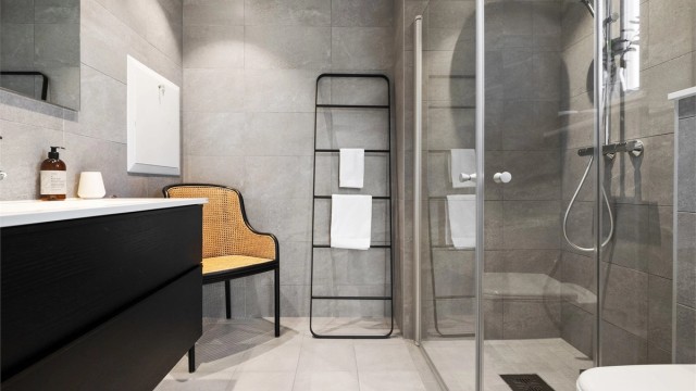 Baderomsinnredningen har sorte, glatte fronter og består av en heldekkende servant på en skuffeseksjon og et stort speil med god belysning.