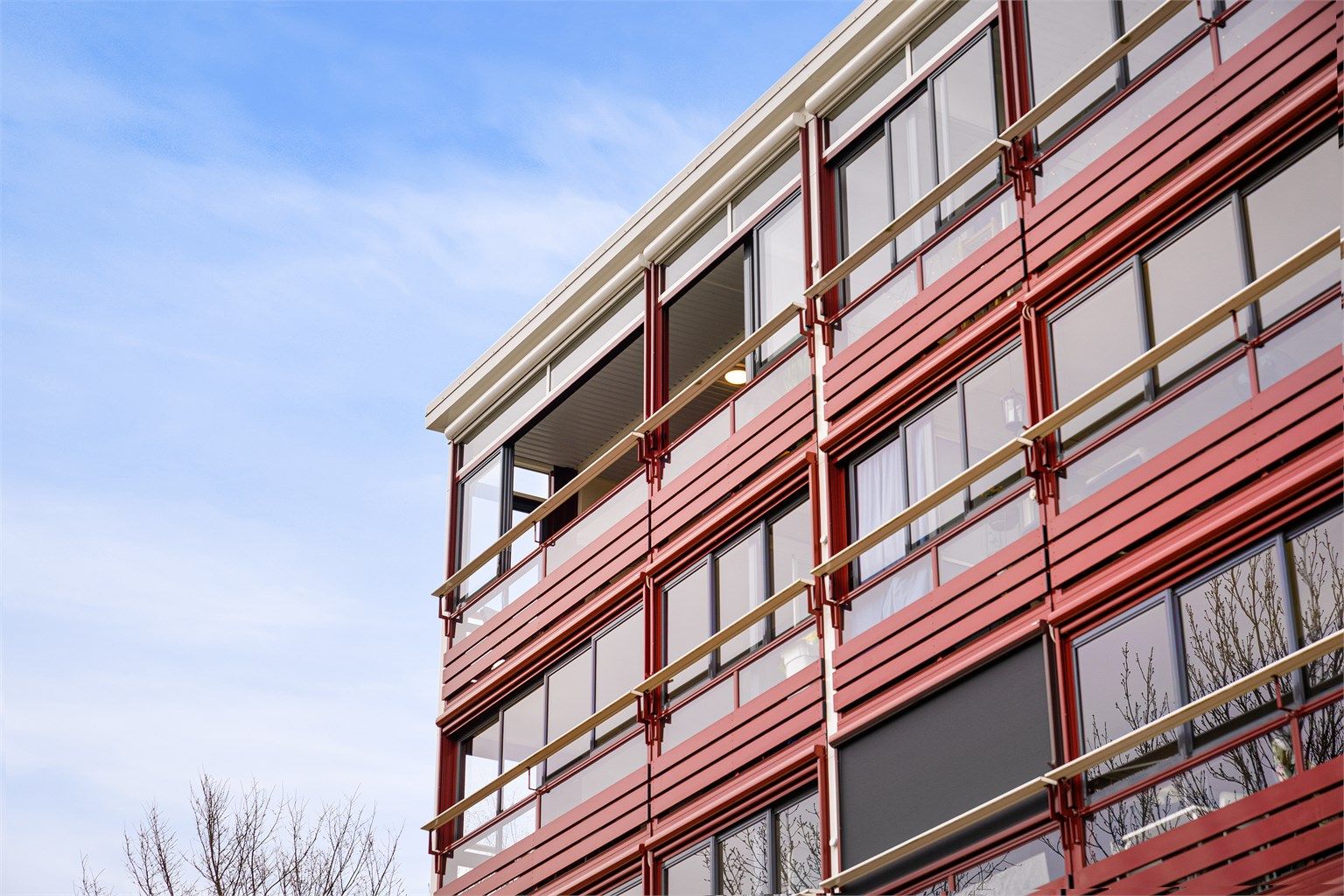 Et nærbilde av fasaden som viser de gjennomgående, innglassede balkongene.