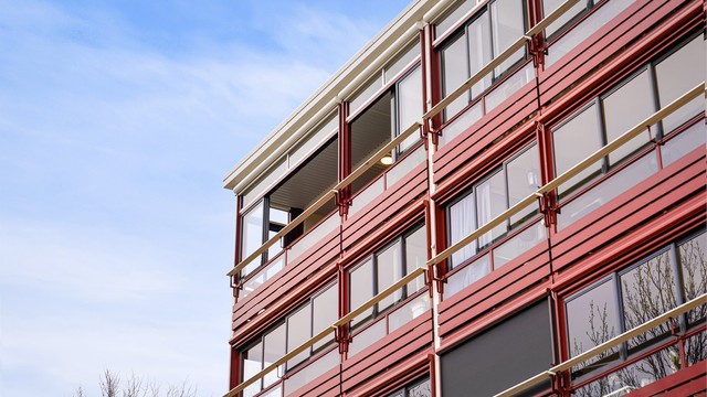 Et nærbilde av fasaden som viser de gjennomgående, innglassede balkongene.