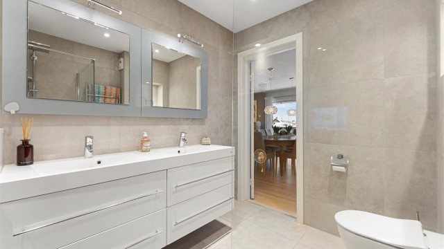 Badet er utstyrt med vegghengt toalett og nedstøpte varmekabler i gulvet for komfort.