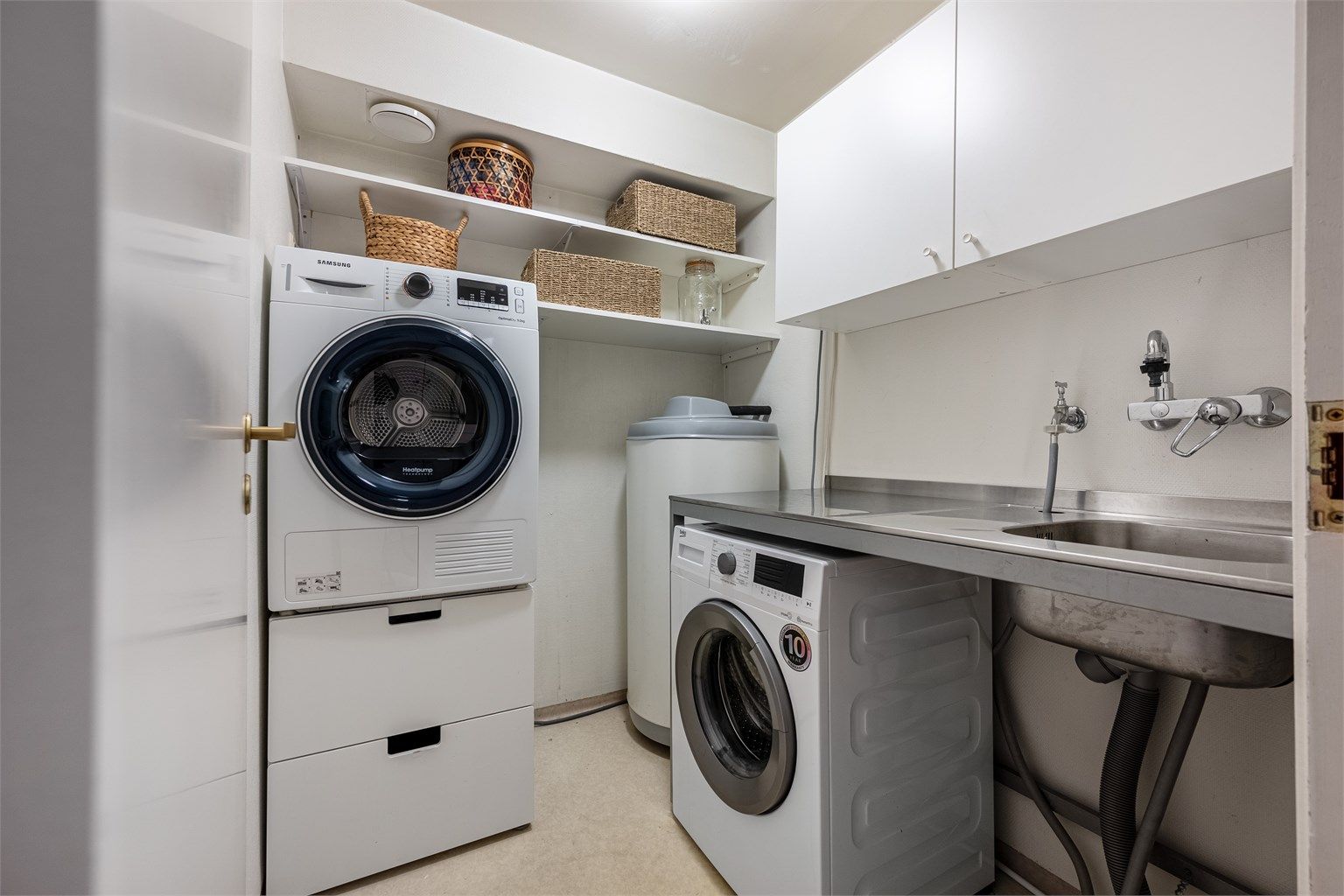 Det er romslig og praktisk vaskerom med plass til både vaskemaskin og tørketrommel. Oppbevaring i skap. Et meget smart og herlig rom. Belegg på gulv.  
