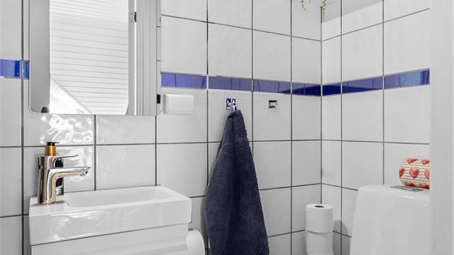 Det andre badet har gulvstående toalett og dusj, praktisk plassert i nærheten av entréen.