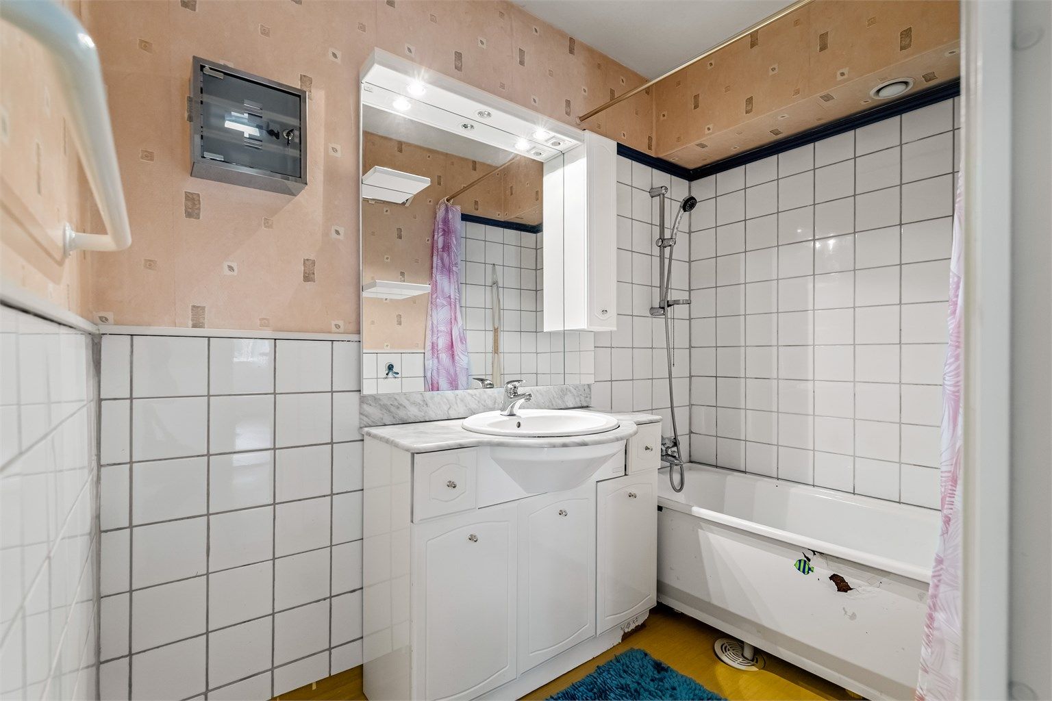 Baderom innredet med badekar, profilerte skapfronter, benkeplate i stein og nedsenket servant.