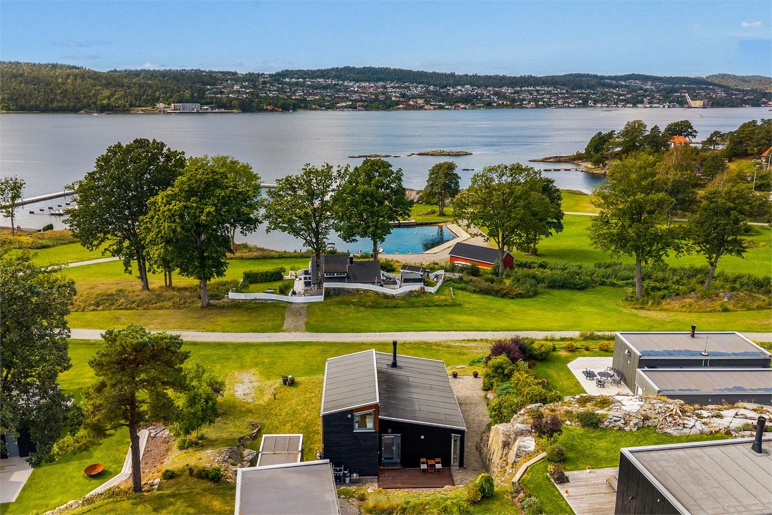 Den sortmalte funkishytta ligger åpent og fint i fremste rekke med utsikt utover sjøen. 