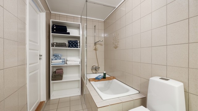 Badet har toalett fra 2022 og innfliset badekar med dusjvegg av glass samt veggmontert dusjarmatur.