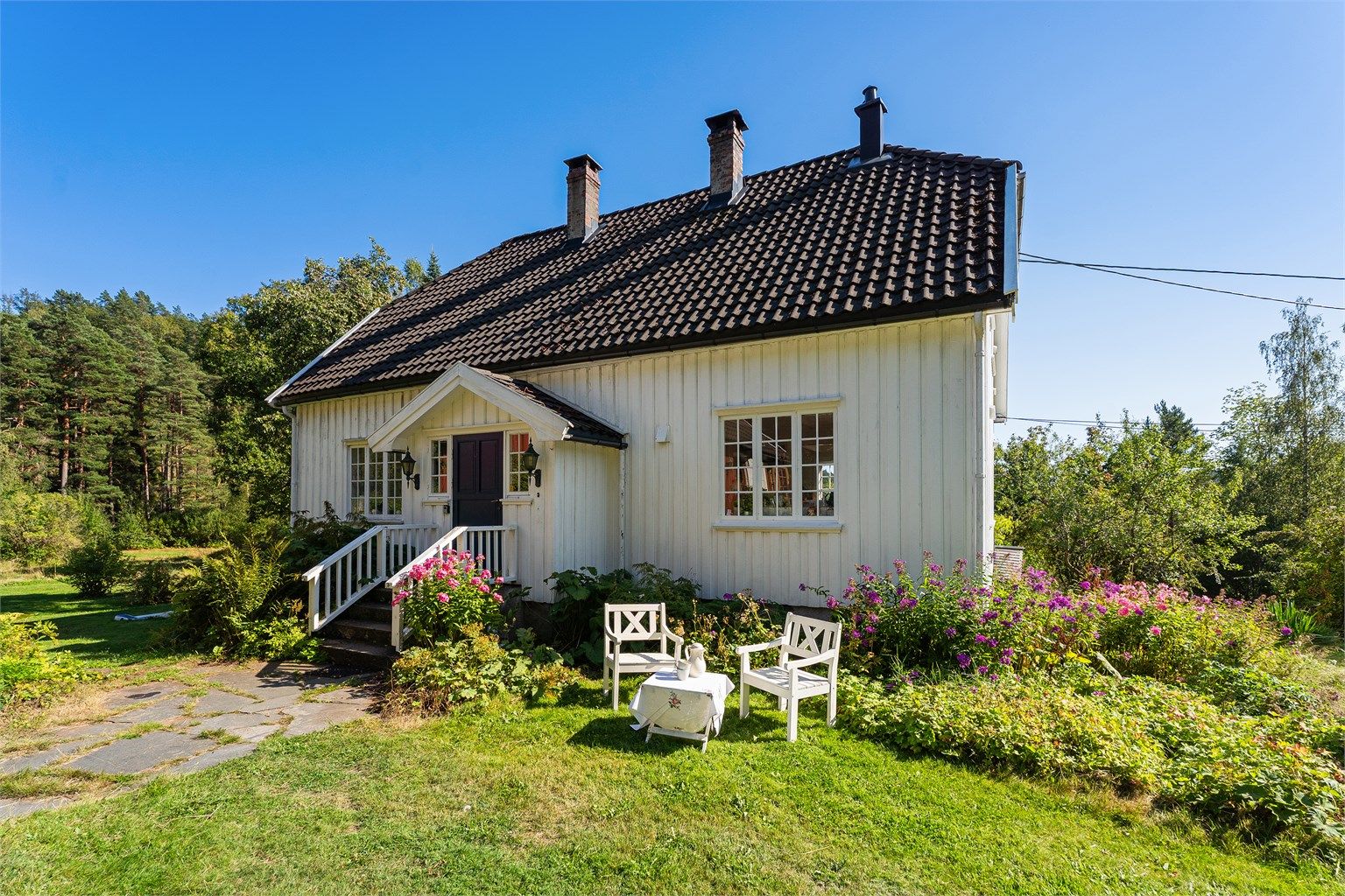 Solrik eiendom med flere lune uteplasser. Inngangspartiet.