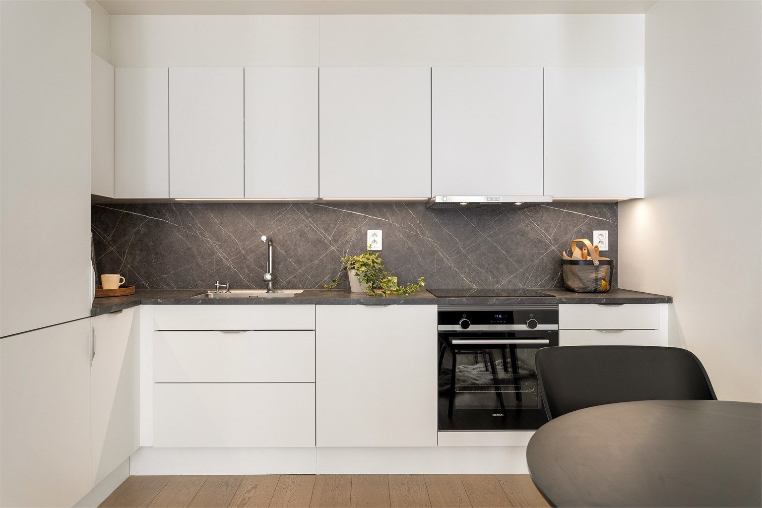 Minimalistisk HTH-kjøkken med glatte fronter, laminatbenkeplate og integrerte hvitevarer.