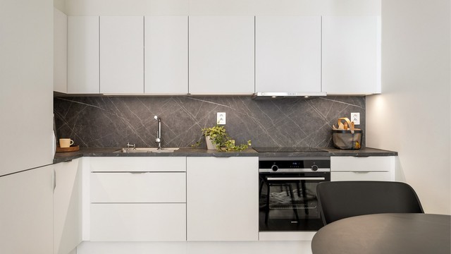 Minimalistisk HTH-kjøkken med glatte fronter, laminatbenkeplate og integrerte hvitevarer.