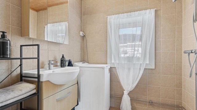 Badet er innredet med vegghengt servantinnredning, speilskap med overlys og gulvstående toalett