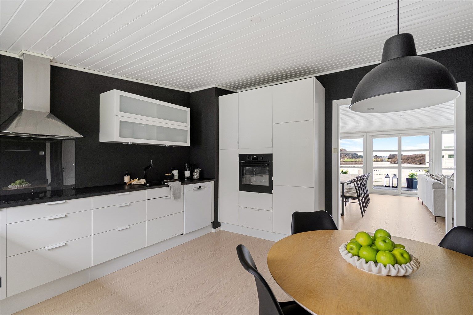 Kjøkken er fra IKEA og har rikelig med skapplass og arbeidsflater på benk. Innredning i hvitt og sort benkeplate. Integrerte hvitevarer. 