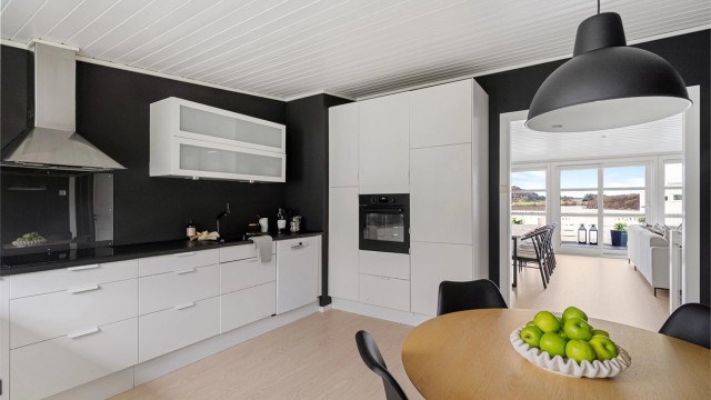 Kjøkken er fra IKEA og har rikelig med skapplass og arbeidsflater på benk. Innredning i hvitt og sort benkeplate. Integrerte hvitevarer.