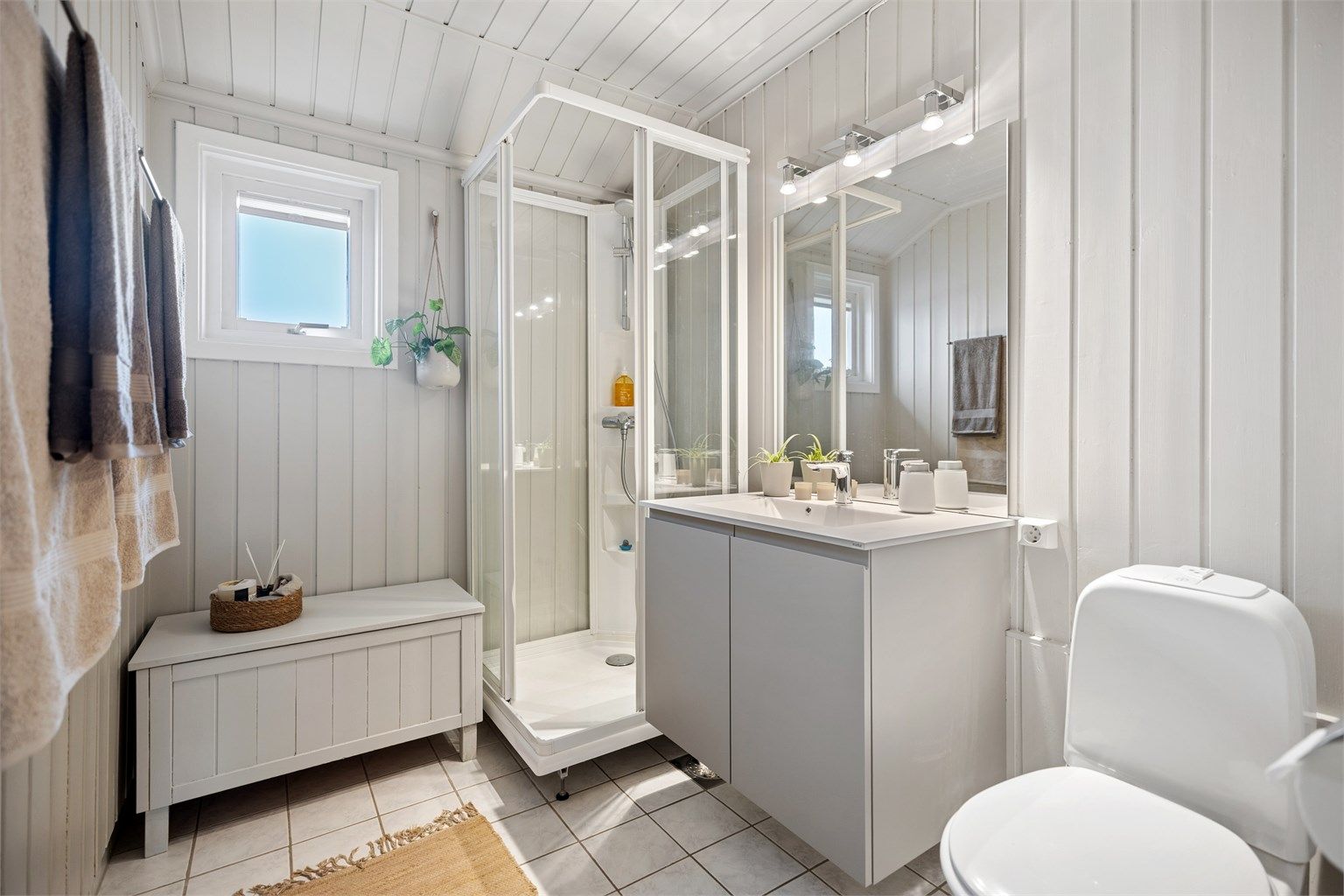 Badet i 2. etasje har flislagt gulv med gulvvarme, dusjkabinett, vegghengt servantinnredning og gulvstående toalett.