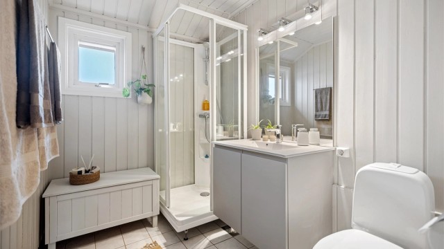 Badet i 2. etasje har flislagt gulv med gulvvarme, dusjkabinett, vegghengt servantinnredning og gulvstående toalett.