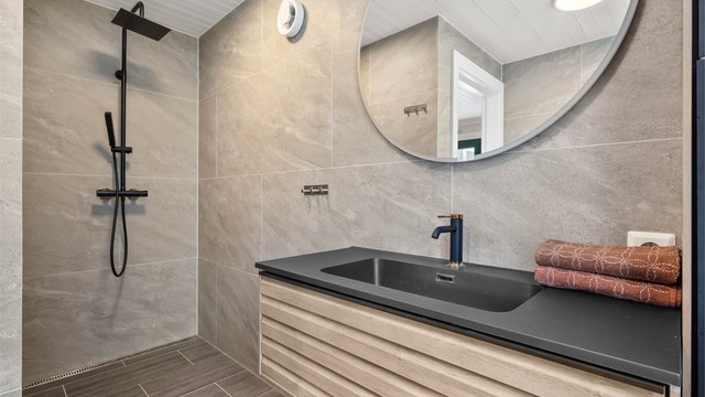 Renovert flislagt bad i hovedbolig med servantskap, dusjhjørne og toalett