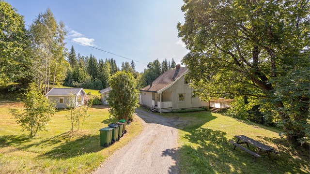 Eiendommen ligger på en skrånende tomt med landlige omgivelser.