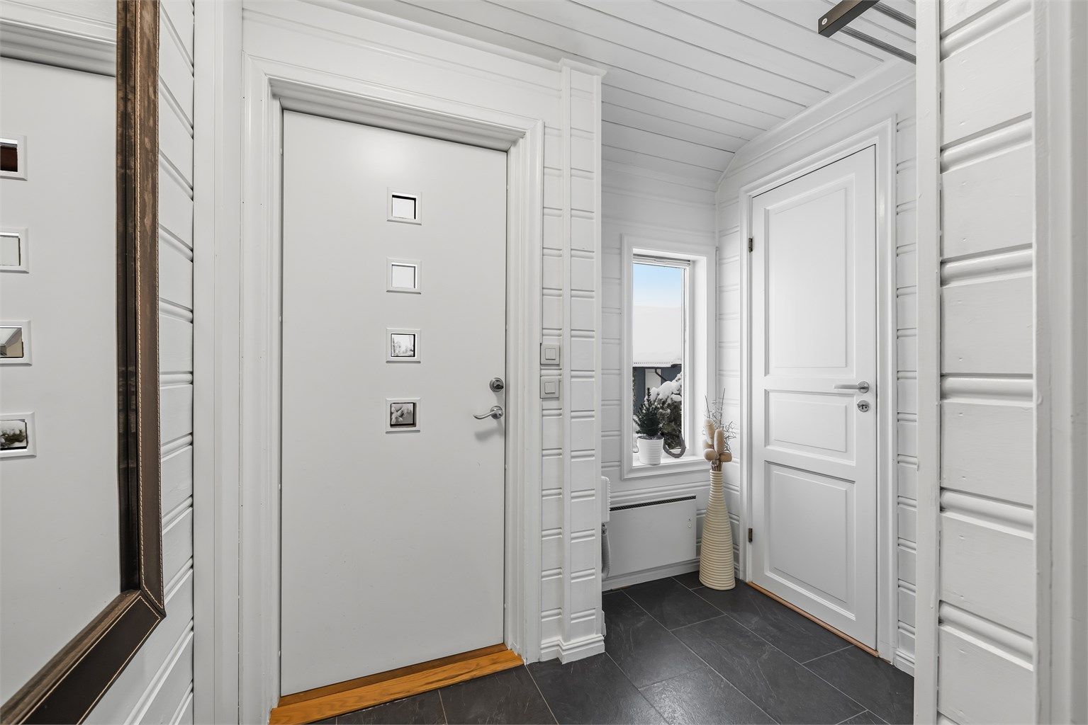 Inngangspartiet har en nyere ytterdør med glassfelt fra 2015 og gulv med laminatfliser