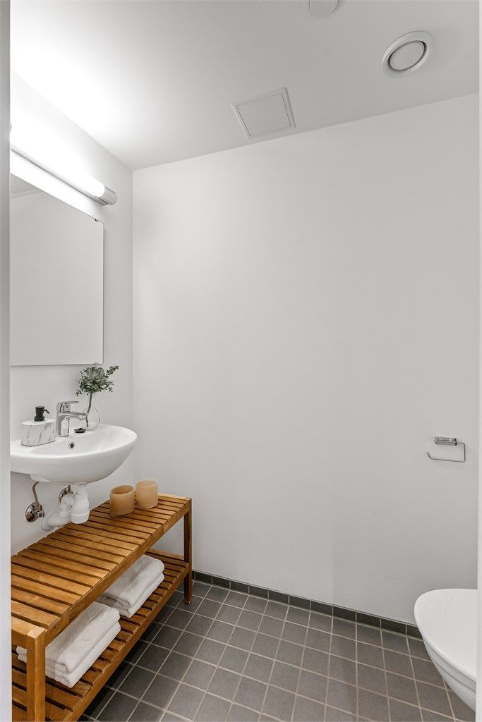 Praktisk toalettrom ved entréen med fliser på gulv med gulvvarme, malte veggflater og malt himling