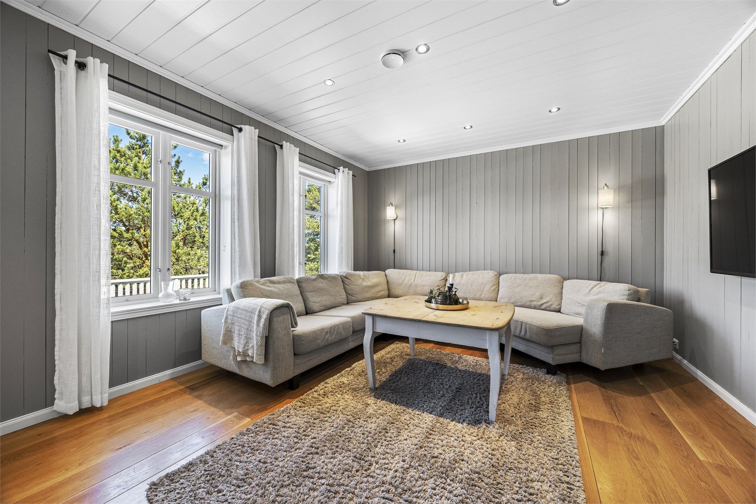 Stuen i hovedetasjen har gjennomgående parkett og plass til en stor sofagruppe.