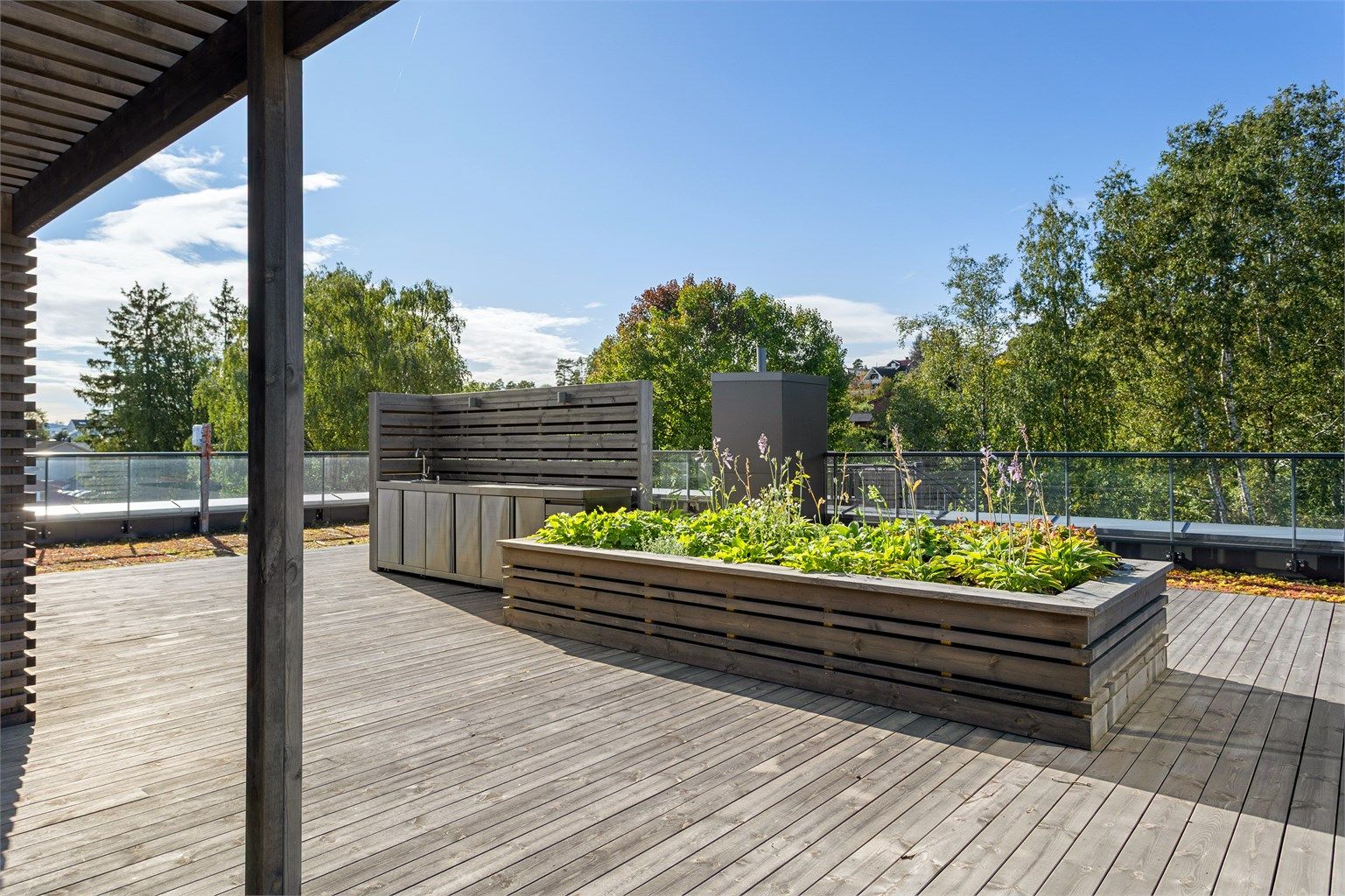 Innebygde plantekasser i tre rammer inn oppholdsplassene på taket.