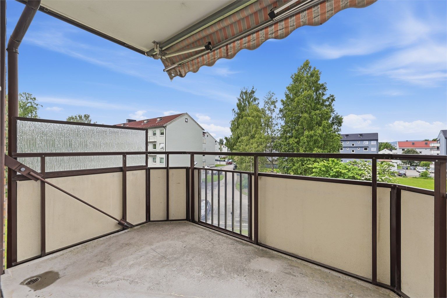 Fra balkongen ser du ut over borettslagets rolige og etablerte fellesområder, sentralt i Lillestrøm.
Foto: Digit Media