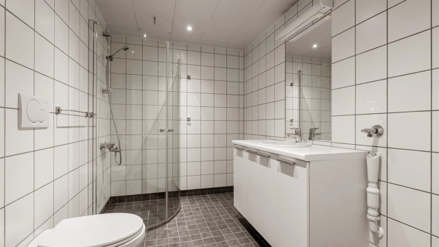 Flislagt bad med gulvvarme. Badet er innredet med vegghengt toalett, servantskap med speil og overlys, opplegg for vaskemaskin og tørketrommelm samt dusjhjørne