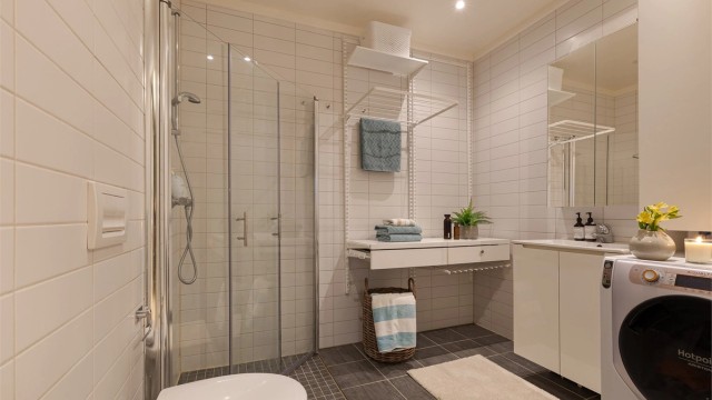 Badet i loftetasje har lyse farger, vegghengt toalett, lekker vask og innfellbare glassdører. Speilskap over vask og downlights i himling.