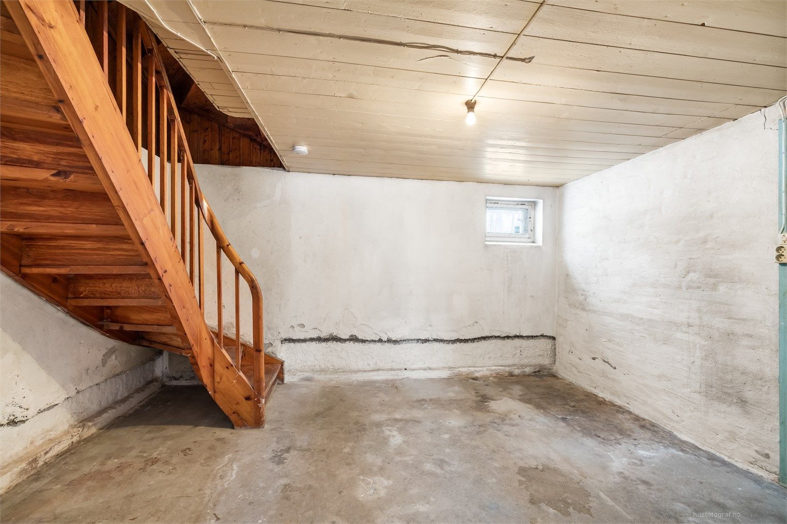 Kjelleren er uinnredet med synlig murgulv og gir rikelig med lagringsplass.
