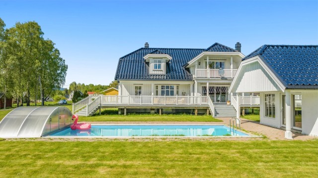 Stor hage med svømmebasseng og tilhørende bassenghus.