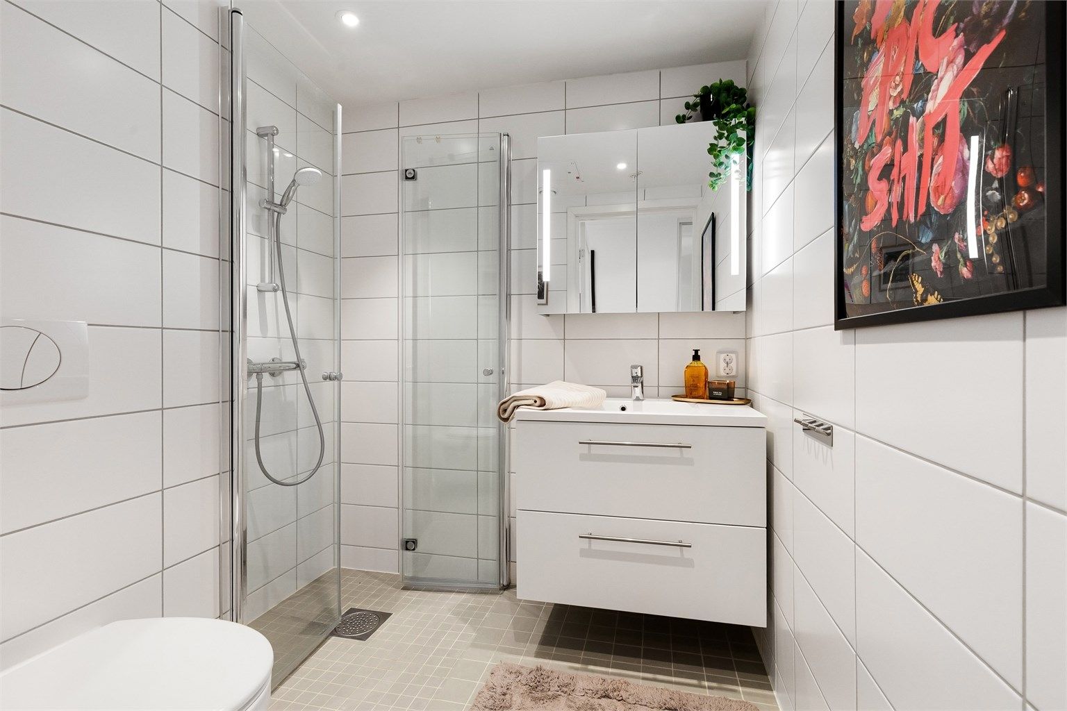 Det andre badet har adkomst fra entréen, og er utstyrt med vegghengt toalett, servantinnredning og dusjhjørne med glassdører.