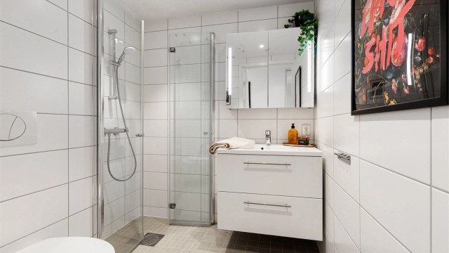 Det andre badet har adkomst fra entréen, og er utstyrt med vegghengt toalett, servantinnredning og dusjhjørne med glassdører.