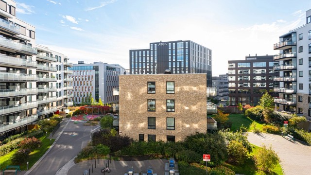 Utsyn over sameiets beplantede gårdsrom med sittegrupper og lekeplass.