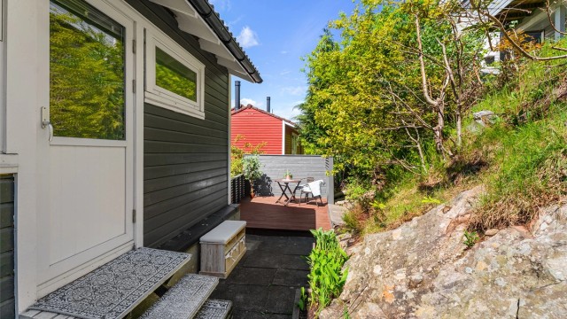 Uteområdet bak er opparbeidet med platting og levegg.