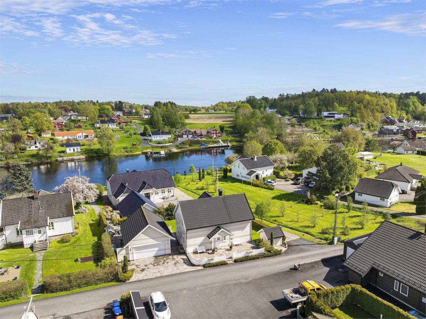 Oversikt over eiendommen med bolighus, garasje og beliggenhet nær elven.