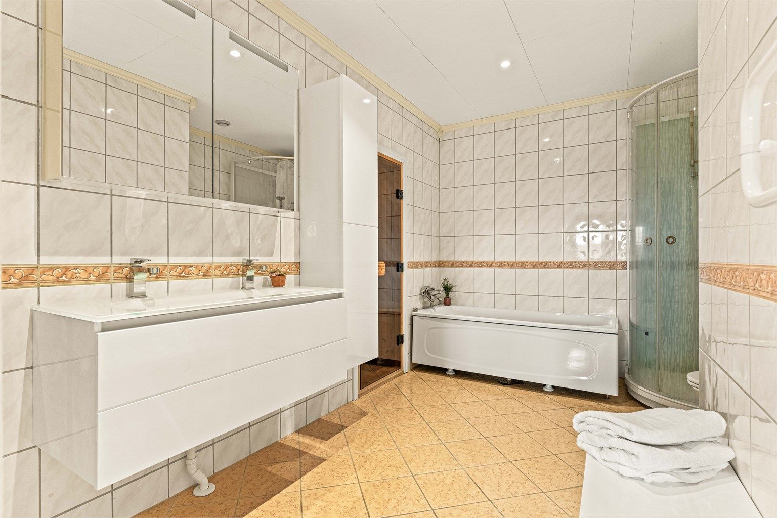 Romslig bad i kjelleren med både dusjkabinett og badekar, samt dobbel servant.