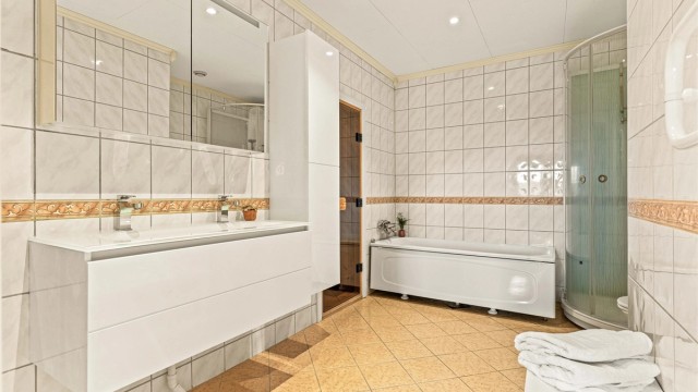Romslig bad i kjelleren med både dusjkabinett og badekar, samt dobbel servant.