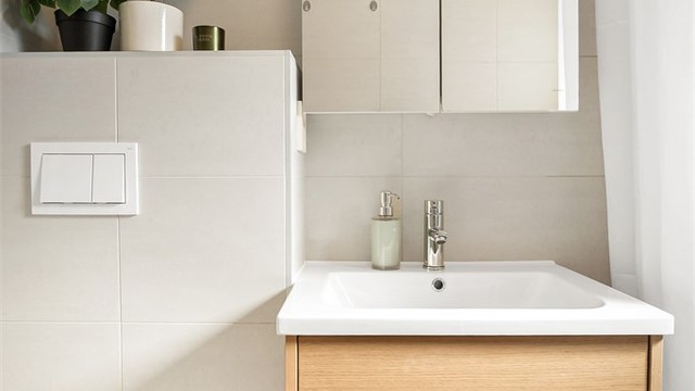 Innredet med badekar og vegghengt toalett. Mekanisk avtrekksvifte i vegg.
