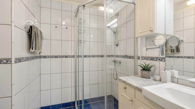 Badet er utstyrt med dusjhjørne med dører og servantinnredning med god oppbevaring.